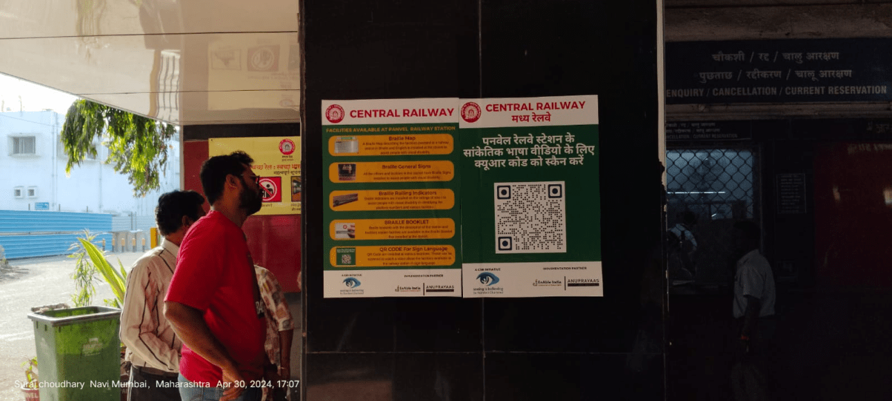 A man reading an accessibility information board at a Central Railway station, featuring Braille maps and sign language QR codes as part of the Anuprayaas initiative.
