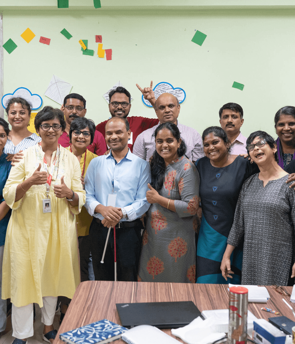 Group of colleagues smiling and posing together in a meeting room.