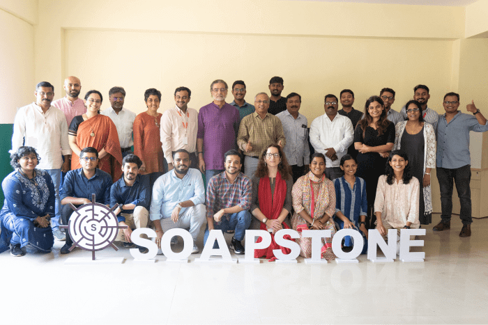Large group of adults posing with a "SOAPSTONE" sign and a target-maze logo.