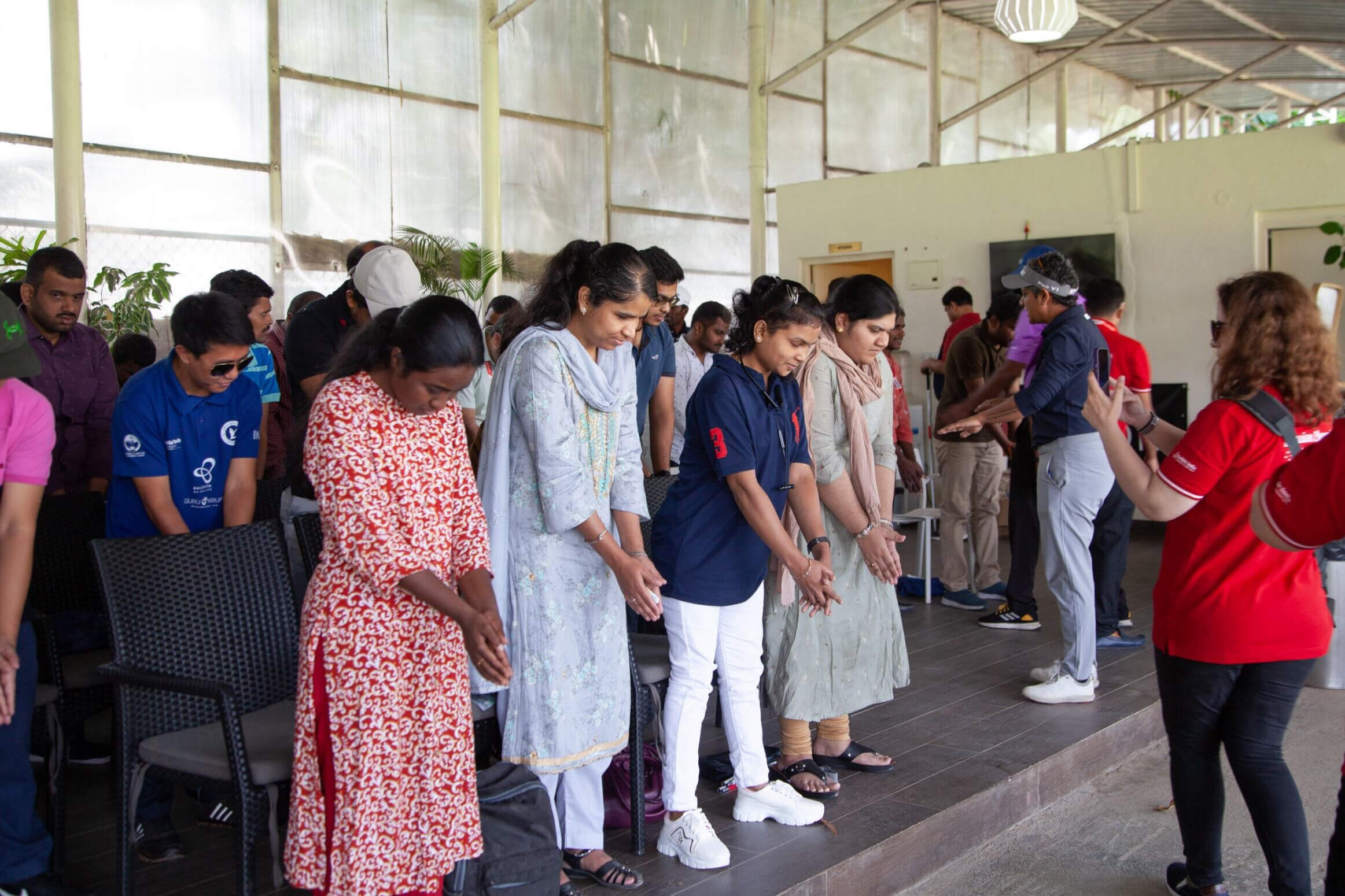 Group of adults practicing guided hand movements during a training session indoors.